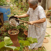 Pair of Daily Dump Prithvi Khambas home composters in outdoor garden with young girl adding kitchen waste to one.