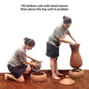 Pair of Daily Dump Prithvi Khambas home composters in outdoor garden with young girl adding kitchen waste to one.