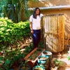 Daily Dump Bamboo leaf composter 32 inches diameter in use in community garden for composting dried leaves with 2 housekeeping staff pressing down to compress pile 