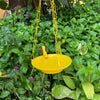 Yellow Bird feeder hanging 3 D against corrugated background