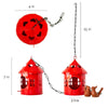 Red hanging metal birdhouse with chain with sparrow in outdoor garden