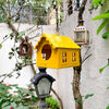 Red hanging metal birdhouse with chain with sparrow in outdoor garden