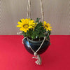 Black hanging pot with flower against corrugated background