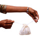 small plain muslin pouch closed with drawstring with loose soapnuts in basket and on ground